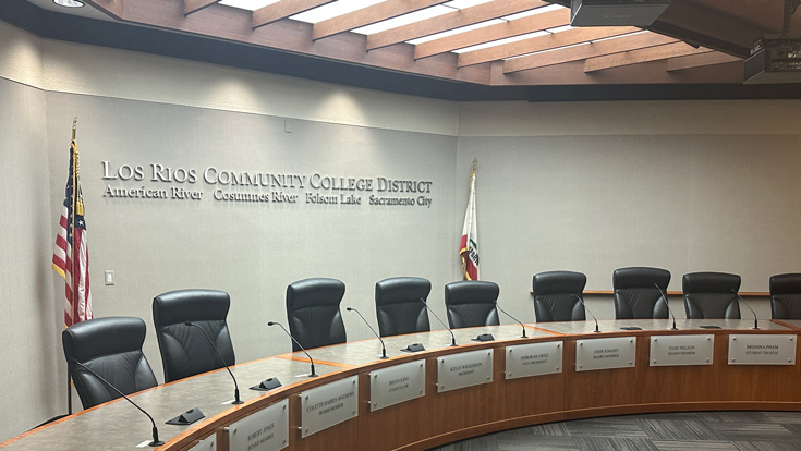 Interior of the board room showing a sign on the wall with the district and four college names