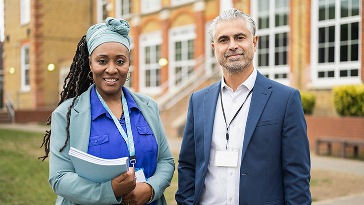 Two high school administrators standing outside of a building