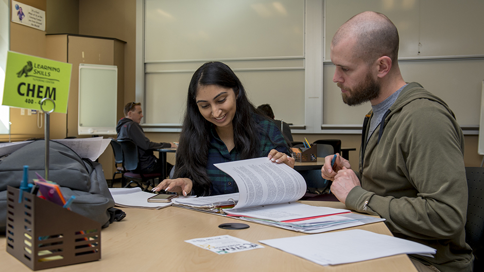 A Male tutor helping a female student with her Chemistry homework.